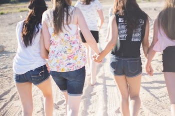 four woman holding hand white walking