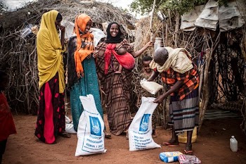 four women standing near white-and-blue sack outdoor