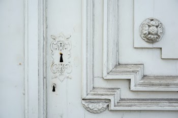Fragment of a wooden carved door painted with white paint. 