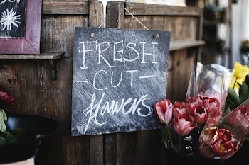 fresh cut flowers sign hanged on door beside flowers