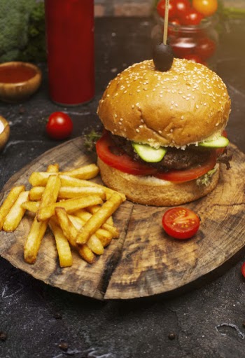 Fresh tasty beef burger and french fries on wooden table, ketchuo, tomatoes, vegetables Free Photo