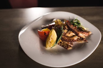 Fried vegetables and octopus on plate in cafe