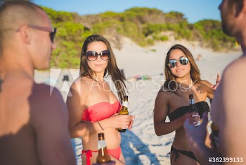 Friends drinking beer on beach during sunset