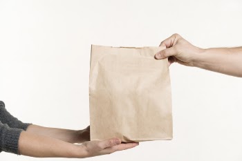 Front view of pair of hands holding paper bag Free Photo