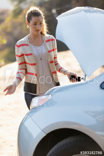 Frustrated woman looking at engine at roadside