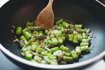 Frying asparagus with onion in a pan 