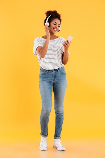 Full length image of happy african woman listening music Free Photo
