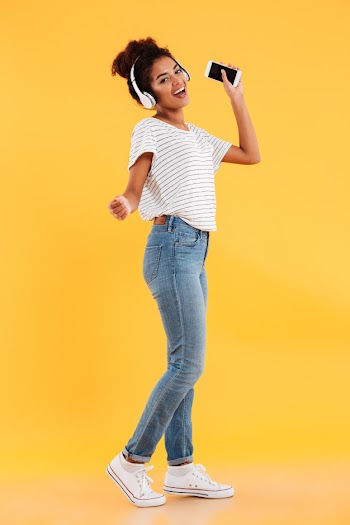 Full-length image of pleased african woman dancing and listening music Free Photo