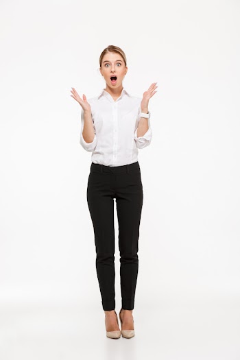 Full length image of shocked blonde business woman holding hands near head and  with open mouth over white wall Free Photo