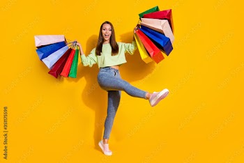 Full size photo of positive cheerful girl enjoy shopping buy many off-sales hold bags wear green good look clothes sneakers isolated bright shine yellow color background