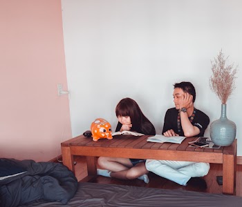 Girl and Boy Sitting in Front of Brown Wooden Coffee Table
