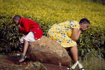 Girl and Woman Sitting on Brown Rock