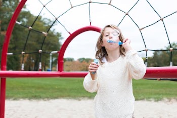 Girl Blowing Bubbles At Park
