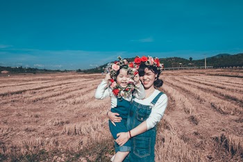 Girl Carrying Toddler While Holding Wreath on Field
