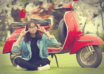 Girl Doing Peace Sign Indian Sitting in Front of Red Scooter Motorcycle