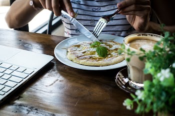 Girl eating pancake with honey in a coffeeshop 