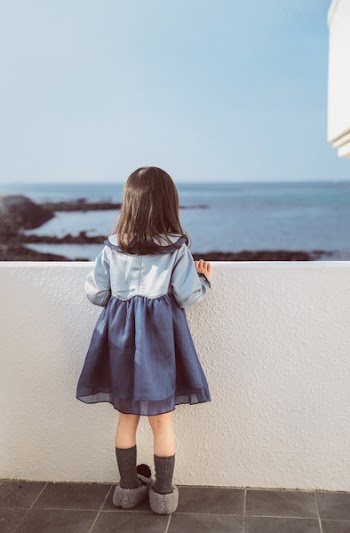 Girl Holding on White Concrete Fence