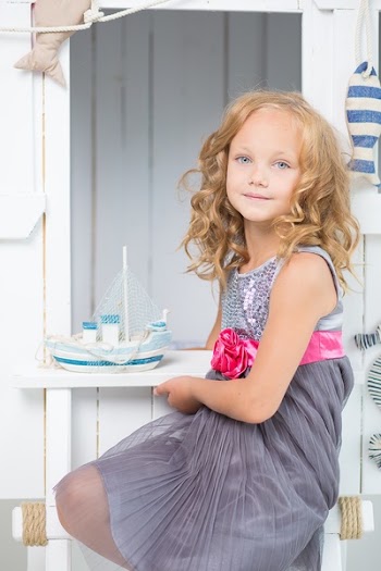 Girl in Grey Sequin Pleated Mini Dress Sitting Near White
