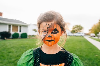 Girl in Orange Face Paint Standing on Lawn