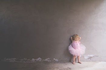 girl in pink tutu dress leaning on the wall