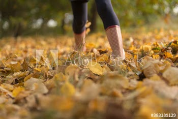 Girl in rubber boots walking in autumn leaves