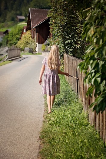 Girl in White and Purple Dress Walking Along Green Grass Field during Daytime
