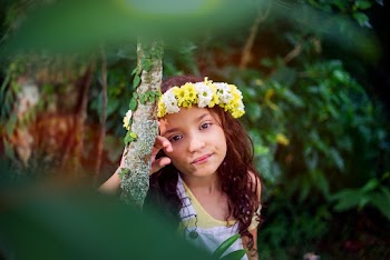 Girl in White and Yellow Tank Top and Yellow and White Floral Headdress Leaning on Tree Trunk