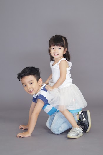 Girl in White Dress Sitting on Crawling Boy's Back