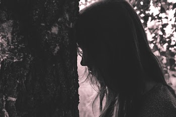 Girl leaning against the tree