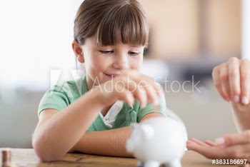 Girl placing coins into piggybank