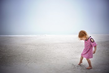 Girl playing on sand near the ocean during day time