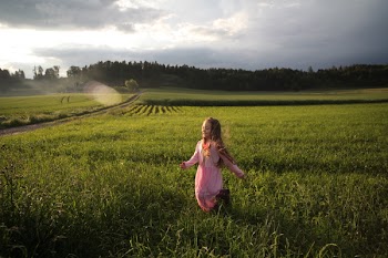 Girl Running on Green Grass Field Near Open Road