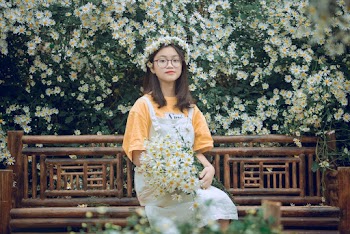 Girl Sits on Bench With Bouquet of Daisies