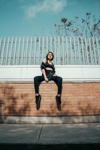 girl sitting on brown concrete wall
