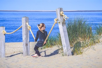 Girl Sitting On Rope At The Fence On Sand
