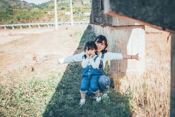 Girl Sitting on Woman's Lap Beside Brown Plants