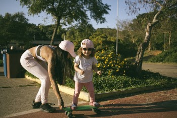 Girl Skateboarding While Woman Holding