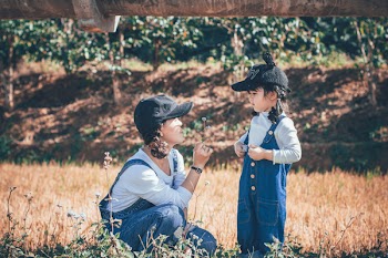 Girl Standing Beside Woman Sitting On Grass