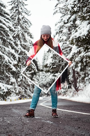 Girl Standing On Road Between Trees While Holding Mirror