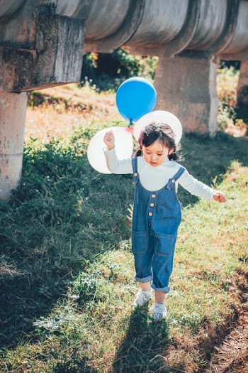 Girl Stepping on Grass While Holding Balloons