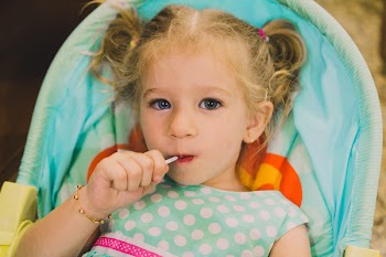 Girl Sucking Lollipop While Sitting on Bouncer Seat