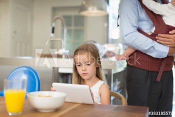 Girl suing digital tablet at breakfast table