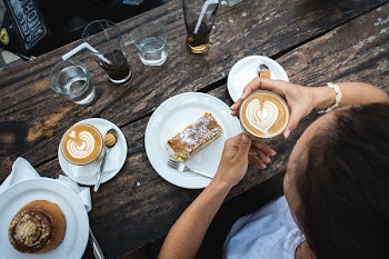 Girl treating herself with flatwhite coffee and cake 