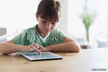 Girl using digital tablet at dining table