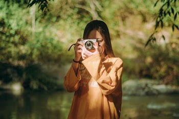Girl Wearing Orange Long-sleeved Shirt Holding Gray Point-and-shoot Camera