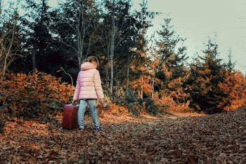 Girl Wearing Pink Down Jacket, Blue Denim Jeans Holding Red Suitcase