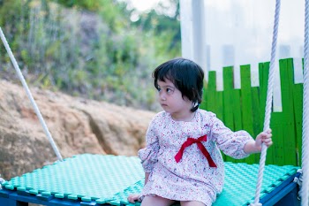 Girl Wearing White Long-sleeved Dress While Sitting on Swing