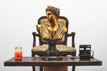 Gold Headbust on Table Near Camera and Votive Candle
