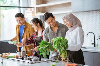 Good friends laughing and talking while preparing meals at table for cooking in kitchen