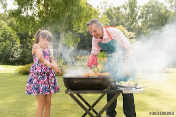 Grandfather and granddaughter barbecuing in summer backyard